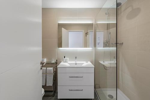 a white bathroom with a sink and a shower at Lisboa Central Park Hotel Suites & Studios in Lisbon