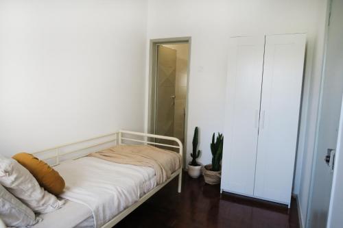 biała sypialnia z łóżkiem i rośliną w obiekcie Lisbon Key Hub - Rooms 6-10 w Lizbonie