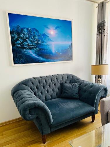a blue couch in a living room with a painting at Sopot Spa Apartament in Sopot