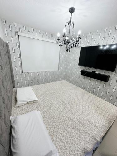 1 dormitorio con cama y lámpara de araña en Departamento Deluxe en Piura