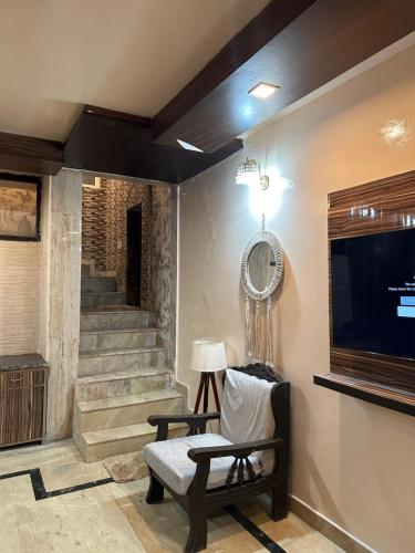 a living room with a tv and a chair and stairs at Cozy Bohemian Studio Apartment - GK2 South Delhi, near M Block Market in New Delhi
