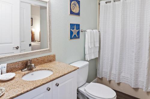 a bathroom with a toilet and a sink and a mirror at Royal Floridian Resort South by Spinnaker in Ormond Beach