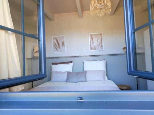 a bed with two pillows in a room with windows at Gîte Ar Friz Vihan in Briec