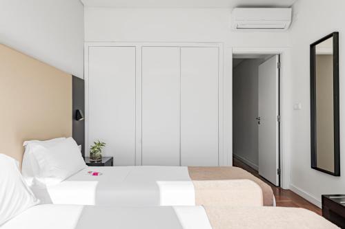 a bedroom with two beds and a mirror at Lisboa Central Park Hotel Suites & Studios in Lisbon