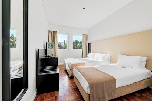 ein Hotelzimmer mit 2 Betten und einem TV in der Unterkunft Lisboa Central Park Hotel Suites & Studios in Lissabon