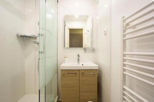 une salle de bain blanche avec un lavabo et un miroir dans l'établissement Les Appartements aux Restanques du Golfe de St Tropez - maeva Home - Appartement spacieux vue mer 2 pièces 5 personnes - Prestige - super Home MAE-2158, à Grimaud