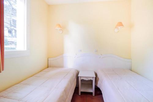 - 2 lits dans une chambre avec une table et une fenêtre dans l'établissement Village Pont Royal en Provence - maeva Home - Appartement 2 Pièces 4 Personnes - Confort MAE-2166, à Mallemort