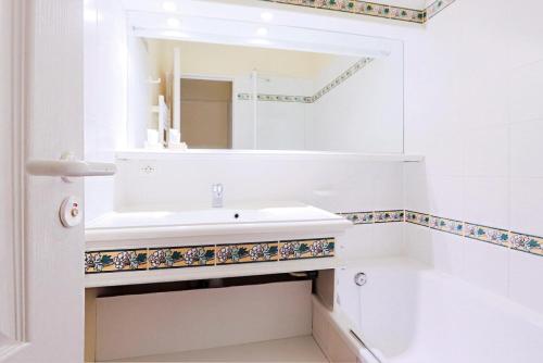une salle de bain blanche avec un lavabo et un miroir dans l'établissement Village Pont Royal en Provence - maeva Home - Appartement 2 Pièces 4 Personnes - Confort MAE-2166, à Mallemort