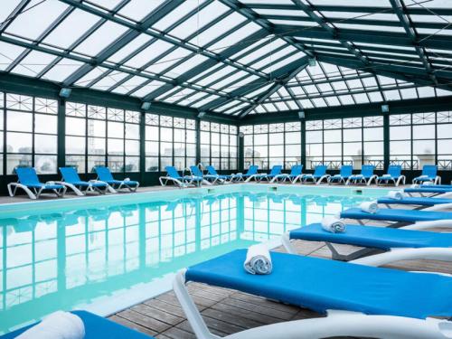 a swimming pool with blue chairs in a building at Résidence Le Beach - maeva Home - 2 Pièces 5 Personnes Confort 67 in Trouville-sur-Mer