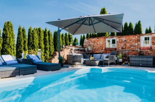 a pool with an umbrella and chairs and a patio at 5 Sterne Centurion Ferienhaus Villa 2 Pools 86 Zoll TV in Aldersbach