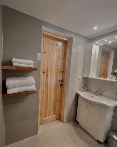 ein Badezimmer mit Waschbecken und Holztür in der Unterkunft Sihena in Skiathos-Stadt