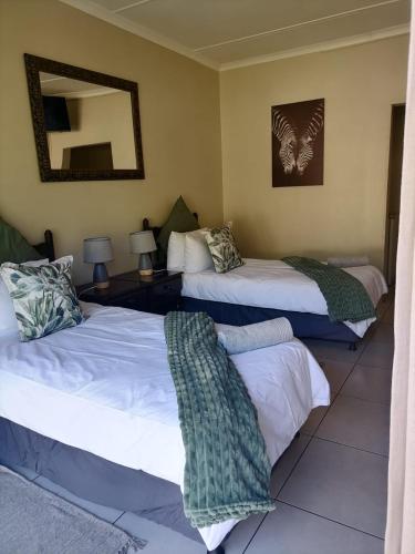a bedroom with two beds and a mirror at Hhusha Hhusha in Malelane