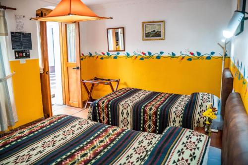 a bedroom with two beds and a yellow wall at Hostal Riviera Sucre in Otavalo