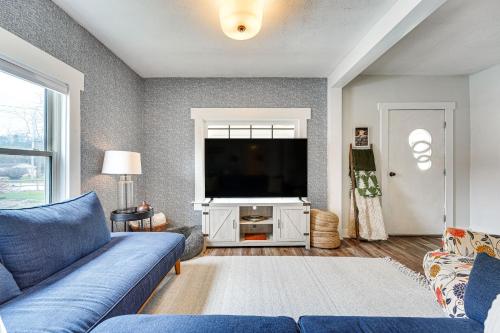 a living room with a blue couch and a flat screen tv at Lovely Ludlow Farmhouse about 1 Mi to Town and Slopes! in Ludlow