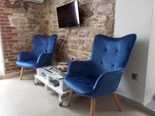 twee blauwe stoelen in een woonkamer met een tafel bij Dora's house in Katarráktis