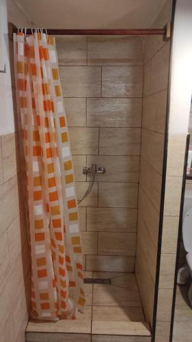 een douche met oranje en witte gordijnen in de badkamer bij La Măcei in Cărbunari