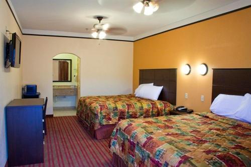 a hotel room with two beds and a bathroom at Guest Inn San Benito/Harlingen in San Benito