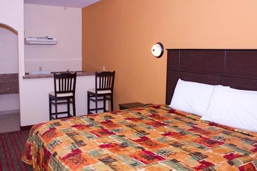 a hotel room with a bed and two chairs at Guest Inn San Benito/Harlingen in San Benito