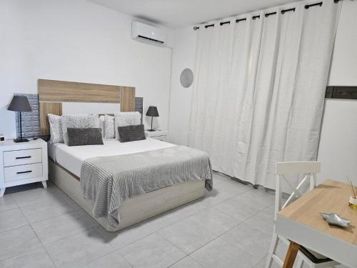 a white bedroom with a large bed and a desk at Casa Kevin in Puerto de Mogán