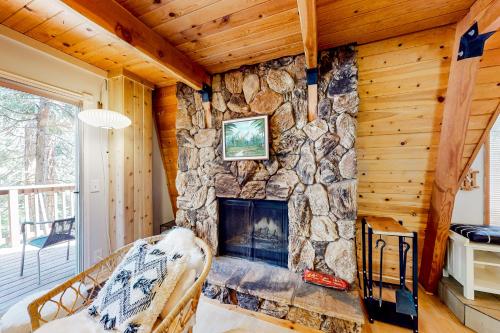 a living room with a stone fireplace in a cabin at Hidden Wonder in Crestline