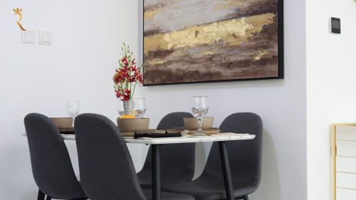 a dining room table with chairs and a painting on the wall at City Nest 2BR - Stylish Urban Oasis in Abu Dhabi