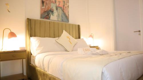 a bedroom with a bed with white sheets and two lamps at City Nest 2BR - Stylish Urban Oasis in Abu Dhabi