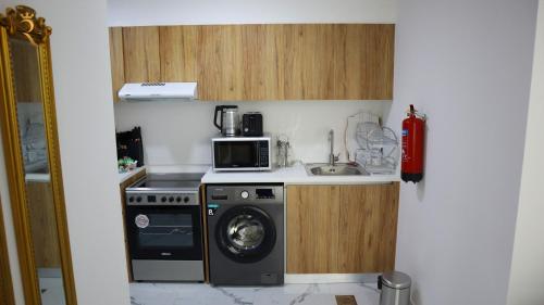 a kitchen with a washing machine and a microwave at City Nest 2BR - Stylish Urban Oasis in Abu Dhabi