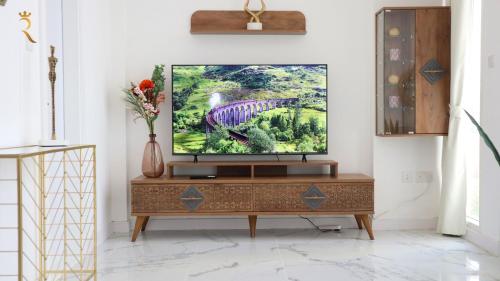 a living room with a television on a dresser at City Nest 2BR - Stylish Urban Oasis in Abu Dhabi