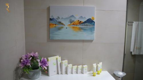 a bathroom with a table with purple flowers and a painting at City Nest - 2BR apartment. in Abu Dhabi