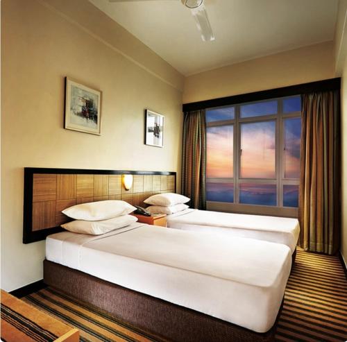 duas camas num quarto de hotel com uma janela em First World Hotel em Genting Highlands