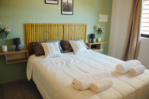 un grande letto bianco con asciugamani sopra in una camera da letto di Acacia a Mendoza