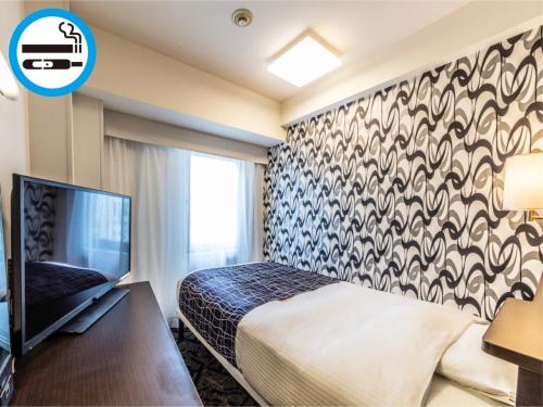 a hotel room with a bed and a tv at APA Hotel Osaka Higobashi Ekimae in Osaka