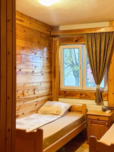 Habitación con cama en una pared de madera. en Apartman Olivera en Žabljak