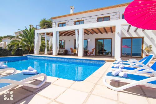 a villa with a swimming pool with chairs and an umbrella at Villa Fustera by Abahana Villas in Benissa