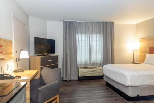 a hotel room with a bed and a desk with a chair at Candlewood Suites New Bern by IHG in New Bern
