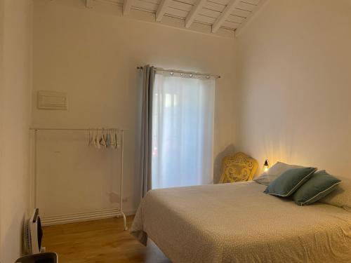 a white bedroom with a bed and a window at Casinha Azul in Horta