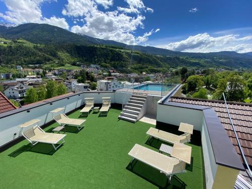 a patio with chairs and a pool on a roof at Dominik Alpine City Wellness Hotel - Adults only in Bressanone