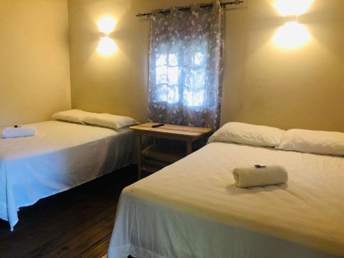 een kamer met 2 bedden en een raam bij Cabaña de campo en el lago de yojoa in Santa Cruz de Yojoa