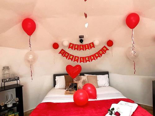 una habitación con una cama con globos rojos y un signo de feliz aniversario en Sol y Luna Glamping, en Málaga