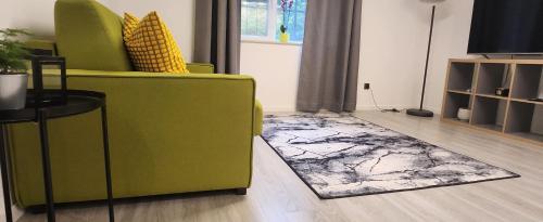 sala de estar con silla verde y alfombra en Apart Hotel Roma, en Sofía
