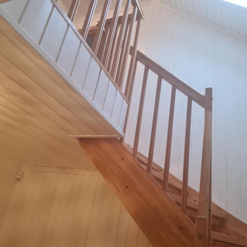 escalera de madera en una habitación con paredes blancas en GG overnatting en Stavanger