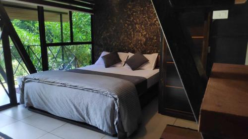 a bedroom with a bed and a large window at Wetlands Wayanad Pool Resort with Natural Waterfalls in Padinjarathara