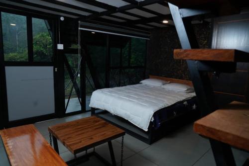 a bedroom with a bed and a table and windows at Wetlands Wayanad Resort with Natural Waterfalls in Padinjarathara