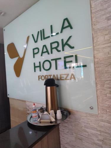 a coffee pot on a table in front of a sign at Villa Park Hotel Fortaleza in Fortaleza