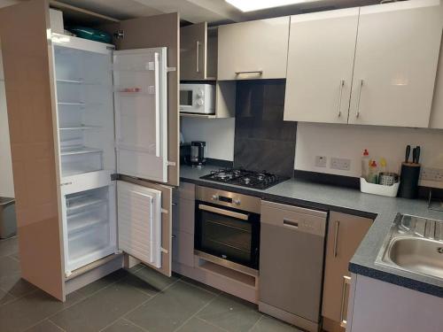 kuchnia z białymi szafkami i otwartą lodówką w obiekcie Flat 1 Cosy and Comfortable in Chester w mieście Chester