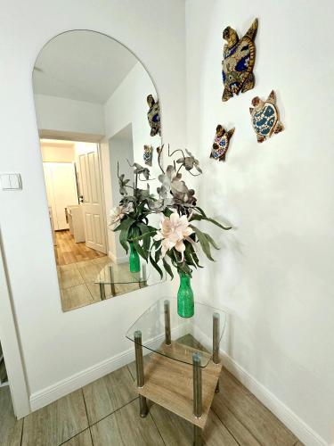 a vase with flowers on a table in front of a mirror at Sopot Spa Apartament in Sopot