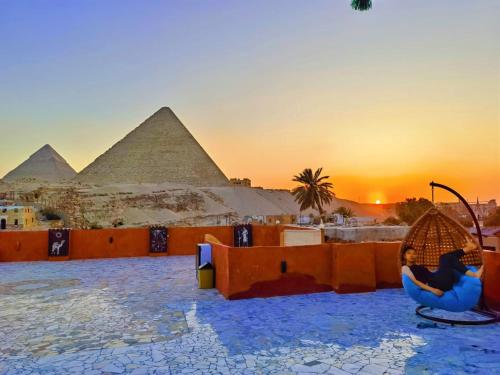 Energy Of Pyramid Hotel في القاهرة: امرأة جالسة على كرسي أمام الاهرامات