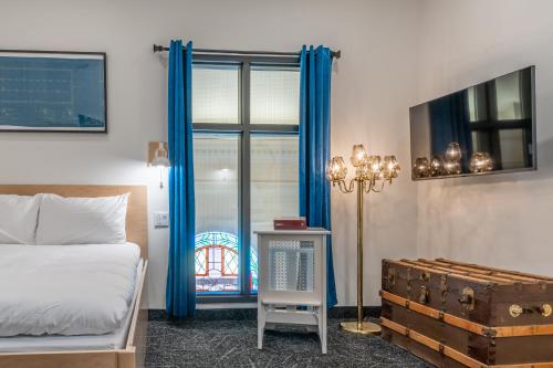 a bedroom with a bed with blue curtains and a suitcase at Le Saint-Crème in Alma