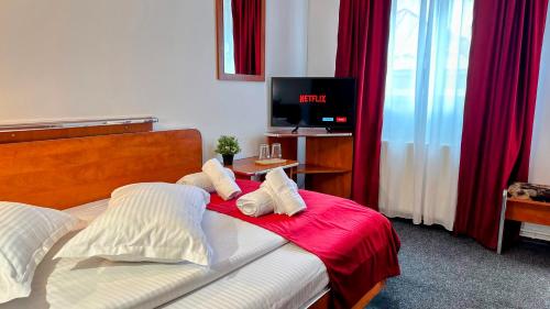 a bedroom with a bed with red curtains and a tv at Valea Albă View - SELF CHECK-IN in Buşteni