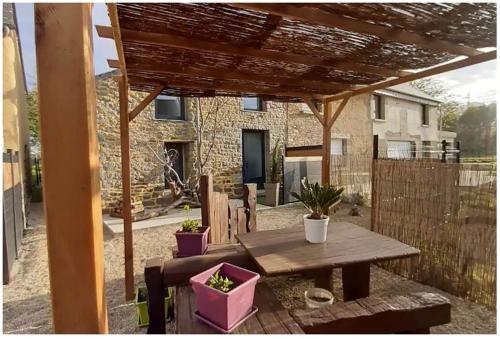 une terrasse avec une table en bois et des plantes en pot dans l'établissement Gites Repère des Fées, à Pleugueneuc
